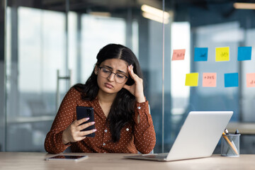 Sad disappointed business woman holding phone in hands, office worker received message with bad...