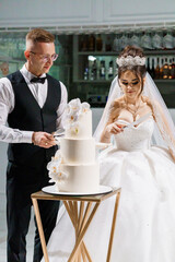 Elegant Wedding Cake Cutting Ceremony with Bride and Groom in Stylish Attire Celebrating their Special Day