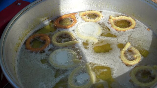 Frying a traditional Turkish donut ring dessert (Halka tatlısı) before dipping it in sugar syrup
