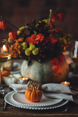 Fall composition. Orange pumpkins, flowers and candles on wooden table. Family elegant Thanksgiving or halloween dinner. Cozy autumn concept, simple handmade decoration, countryside style, wine