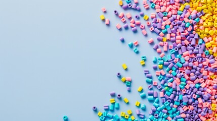 Fototapeta premium Colorful tiny beads spread chaotically over a light blue background, creating a playful and vibrant visual contrast.