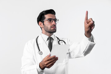 Caucasian smart doctor pointing finger while standing at white background and wearing lab coat. Skilled specialist doctor using medical technology while pointing and looking health data. Deviation.