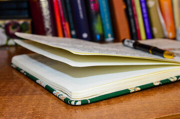 green diary notebook on table on background blurred books bright close up photo preparation for study writing notes education