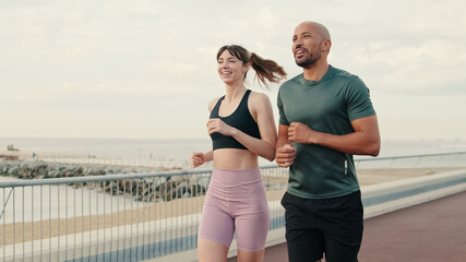 Running woman and man enjoy their summer morning workout. Team sports. Couple goals and motivation. Happy fit people are cheerfully doing sports