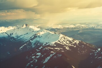 Majestic snow-covered mountain peaks blend with the golden hues of the setting sun, creating a serene and awe-inspiring landscape.
