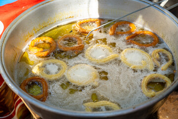 Frying a traditional Turkish donut ring dessert (Halka tatlısı) before dipping it in sugar syrup