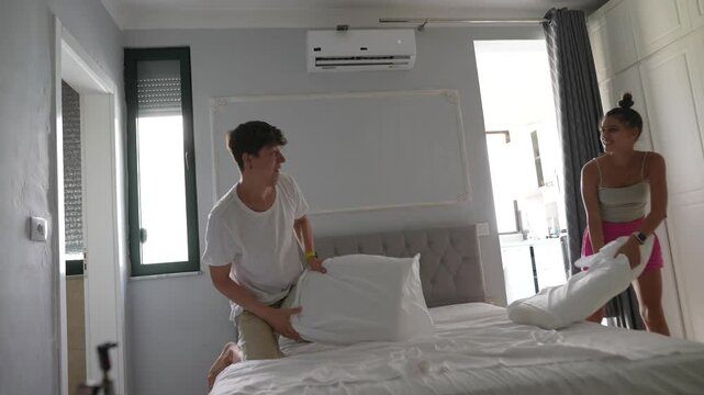 A Couple Engaging in the Activity of Making the Bed Together in a Modern Bedroom Space