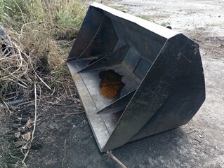 Heavy black steel excavator bucket on the ground. Topics of industry and construction. An item used...