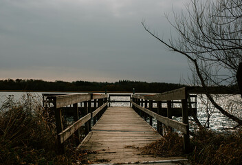 Rustic Dock in a Quiet Lake Under Overcast Sky, Old Wooden Dock at the Edge of a Lake on a Gloomy Day, Weathered Wooden Dock Winter Decay