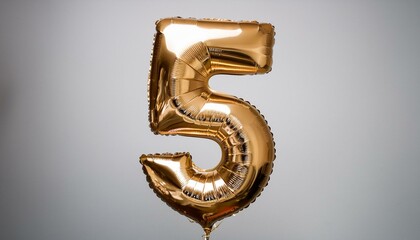 Golden foil balloon 5 floats in neutral space.