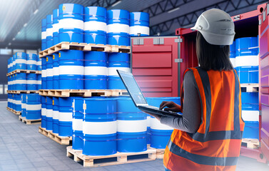 Woman in fuel warehouse. Girl with laptop near barrels on pallets. Fuel tanks near sea container....