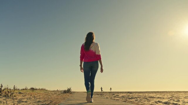 Woman in pink shirt walking on boardwalk