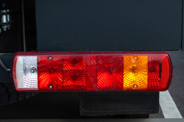 Car taillight. Automobile light for turning warning. Fragment of car or construction equipment. Multi-colored taillight on vehicle. Car lamp for night illumination dimensions. Rectangular taillight