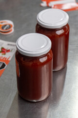 Jars of freshly made rosehip jam in an artisan factory. The jam, rich in color and texture, fills the glass jars to the brim, ready for sealing. Captured during production