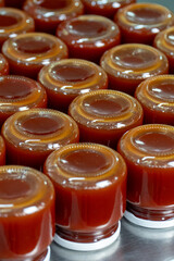 Jars of freshly made rosehip jam in an artisan factory. The jam, rich in color and texture, fills the glass jars to the brim, ready for sealing. Captured during production