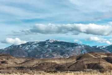 Distant Mountains Covered in Snow Beneath Clouds in Sky, Winter Landscape with Snowy Peaks and Cloudy Skies, Distant Snow-Capped Mountain Peaks and Hillside