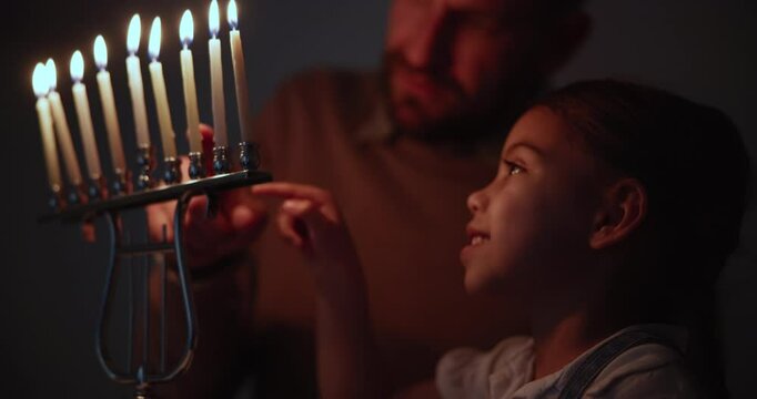 Jewish, tradition and a family lighting candles together in their home for Hanukkah celebration. Culture, religion or holiday with a father and daughter closeup in the dark for their faith or belief