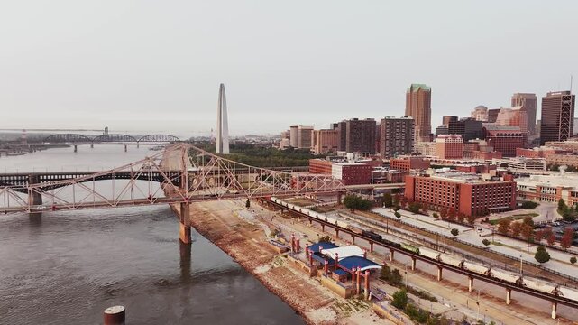 A railroad train coming into downtown Saint Louis, Missouri over the Mississippi River with skyscraper buildings in the background.