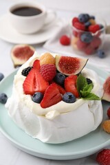 Pavlova cake (meringue dessert) with whipped cream, fresh berries, mint and fig on table, closeup