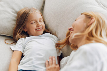 Mother and daughter enjoying a peaceful nap together on a cozy couch with radiant smiles