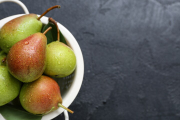 Colander with ripe pears on black table, closeup