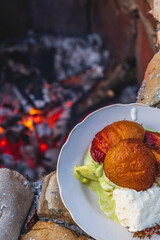 roasted peaches on an open fire with ice cream on a plate close up near the fire