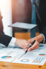 Close-up of hands pointing at financial charts and graphs during a business meeting, discussing data analysis and strategy.