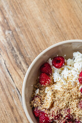 cottage cheese in a bowl with fresh raspberries and ground nuts, top view