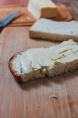 Close-up of a buttered slice of homemade bread with butter in the background