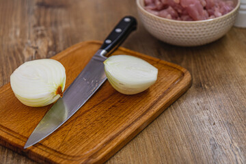 Onion cut into two parts on a board and a knife in the middle