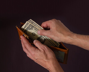 Male hands hold open an old wallet with three dollars