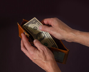 Male hands hold open an old wallet with one dollar