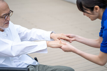 Obraz premium 車いすから立ち上がる介助をする介護施設スタッフ