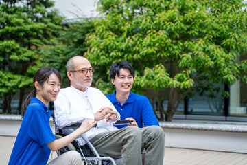 車いすのシニア男性と介護施設スタッフ
