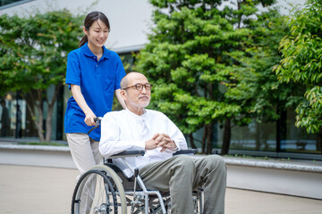 車いすのシニア男性と介護施設スタッフ