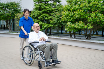 車いすのシニア男性と介護施設スタッフ