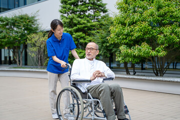 車いすのシニア男性と介護施設スタッフ