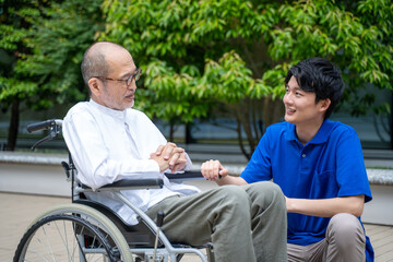 車いすのシニア男性と介護施設スタッフ
