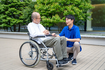 車いすのシニア男性と介護施設スタッフ