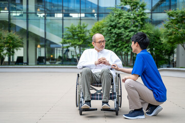 車いすのシニア男性と介護施設スタッフ