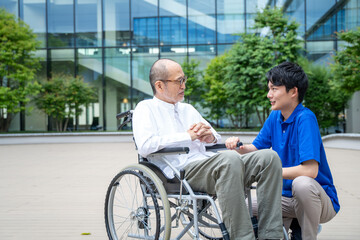 車いすのシニア男性と介護施設スタッフ