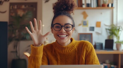 Smiling woman with curly hair waving hello while wearing glasses