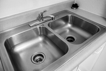Kitchen countertop with a top mounted modern metallic kitchen sink and stainless steel water tap.
