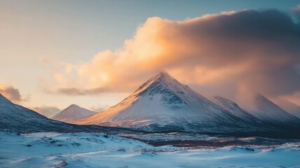 A majestic mountain range with snow-capped peaks and a dramatic cloudy sky at sunset, creating a beautiful and serene landscape.