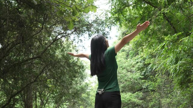 confident asian woman embraces self-love, standing peacefully in serene park at sunset. joyful smile, she enjoys fresh air, breathing deeply, radiates calm and positivity in tranquil surroundings.