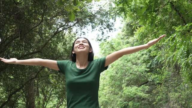 confident asian woman embraces self-love, standing peacefully in serene park at sunset. joyful smile, she enjoys fresh air, breathing deeply, radiates calm and positivity in tranquil surroundings.