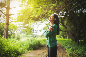 confident asian woman embraces self-love, standing peacefully in serene park at sunset. joyful...