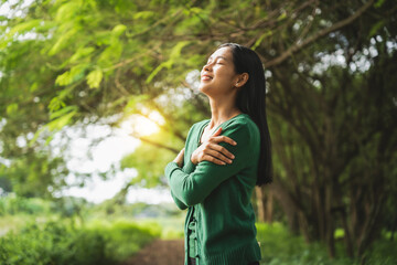 confident asian woman embraces self-love, standing peacefully in serene park at sunset. joyful...
