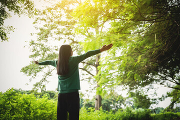 confident asian woman embraces self-love, standing peacefully in serene park at sunset. joyful...