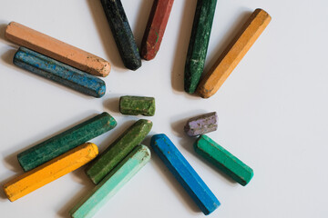 Naklejka premium A collection of used, multi colored crayons or pastels arranged in a loose circular pattern on white background, likely for drawing or coloring.